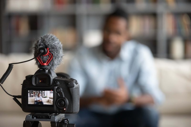 Close-up of a modern camera recording a Black British male coach giving a video tutorial